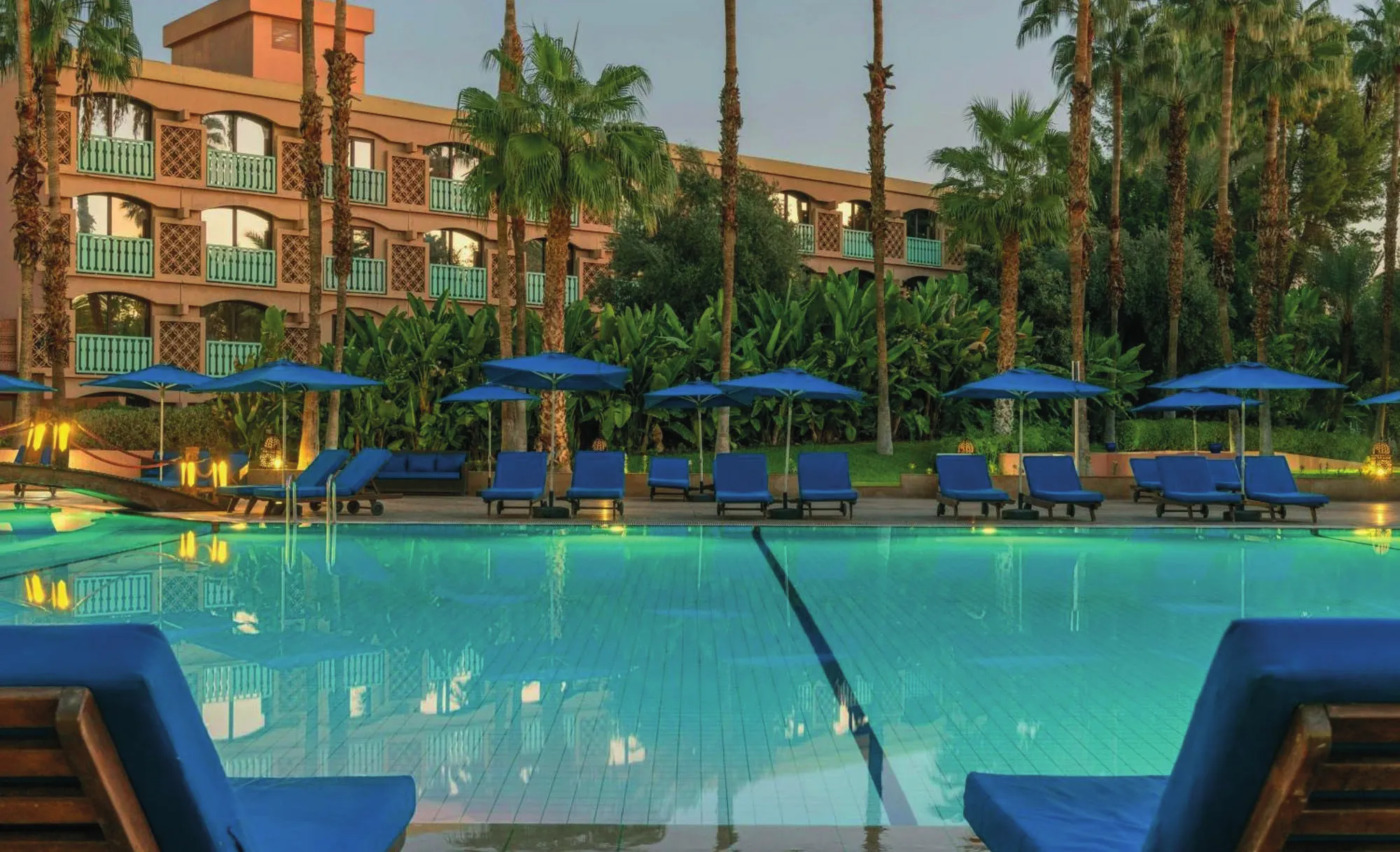 The pool and its blue loungers at dusk, in front of the hotel